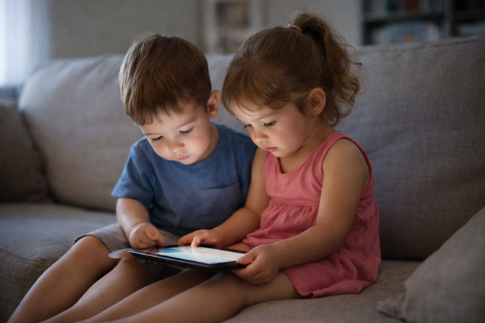 “Ev ortamında birlikte tablet kullanan küçük yaştaki iki çocuk.”