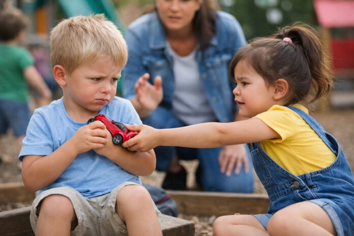 4 yaş çocuğu paylaşmıyor davranışını gösteren, parkta oyuncak paylaşma konusunda anlaşmazlık yaşayan iki çocuk ve müdahale etmeye çalışan ebeveyn